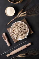 Whole grain wheat raw apulian pasta called Pizzarieddi or maccaruni in a bowl on black table. Fresh...