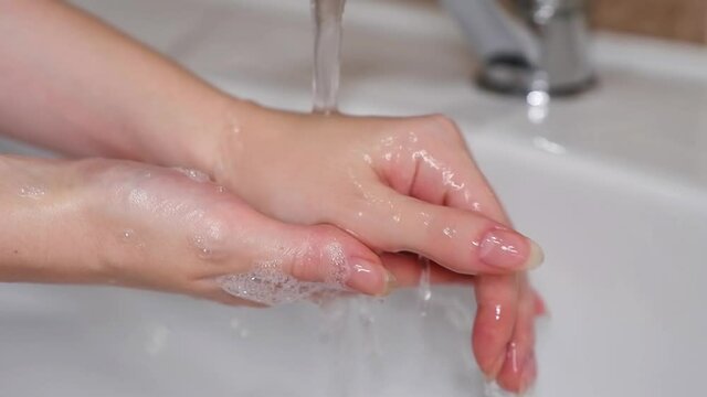 A woman washes soap off her hands with tap water. Hand disinfection. Slow motion.