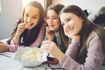 A pajama party with teens eat popcorn on the bed