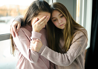 Teenage girl consoling her sad friend on her bedroom