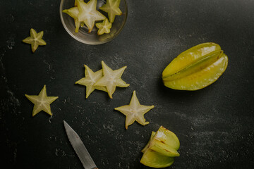 Preparing a fresh star fruit sliced in a dark background