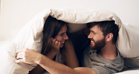 Obraz premium Weekends were made for comfort. Shot of a happy young couple covering themselves with a blanket on the bed at home.