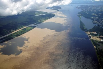 Naklejka premium The Meeting of Waters (Portuguese: Encontro das Águas) is the confluence between the Rio Negro, a river with dark (almost black coloured) water, and the sandy-coloured Amazon River or Rio Solimões. 