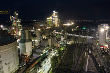 Aerial view of cement factory with high concrete plant structure and tower cranes at industrial...