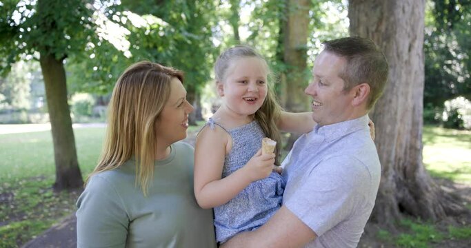 Happy family enjoying time together at park with girl eating ice cream