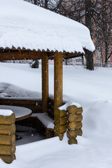 a fragment of a gazebo in a winter park whose roof is covered with snow