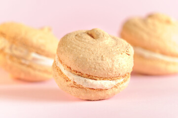 Beige macaroons on a pink background. Selective focus with blurred background. Daylight