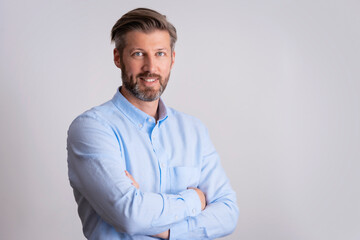 Smiling businessman standing with arms crossed at isolated white background