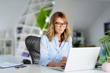 Businesswoman working on her laptop while sitting at the office