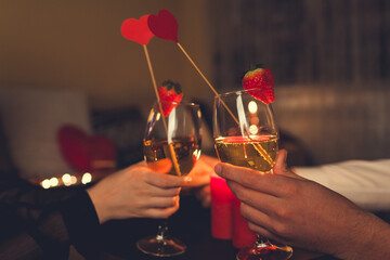 Valentines Day couple in love clinking glasses drinks wine with strawberries having romantic dinner celebrating at home