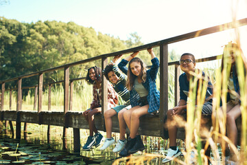 Obraz na płótnie Canvas Life is sweet up the creek. Shot of a group of teenagers sitting on a bridge in nature at summer camp.