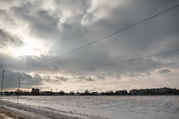 Winter muddy road between fields under clouds