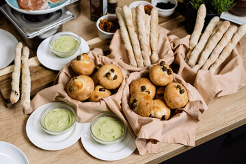 Buns with raisins, a few buns are laid out on pretty fabric. Breadsticks all around.
