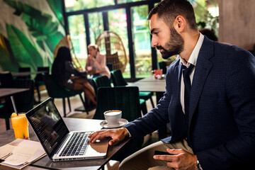 Young businessman working at cafe using laptop.