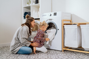 Woman spends time with young child in laundry room, bathroom, performs household duties on...