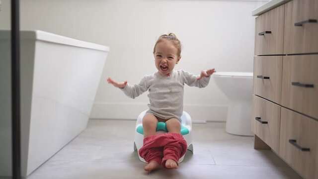 An Adorable young baby child sitting and learning how to use the toilet 