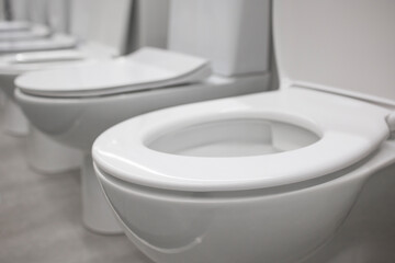 Close up view of row of modern new white toilet bowls in a plumbing store.