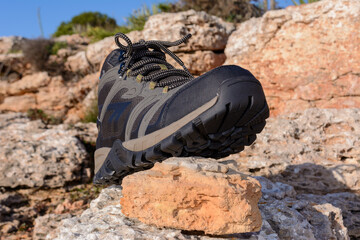 Olive green hiking boots on a natural background of sea and rocks