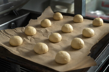 Hamburger buns with sesame seeds prepared for baking. Baking sheet with blanks.