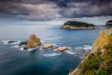 Fototapeta na wymiar Costa rocosa en la que destacan islotes de piedra con un cielo nublado