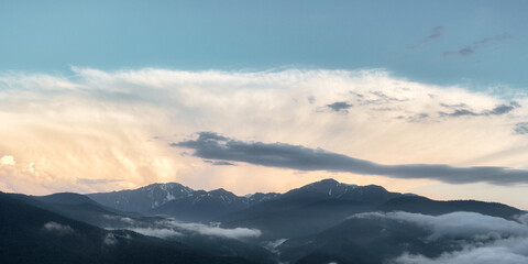 Fototapeta na wymiar The setting sun illuminates the clouds over the mountain peaks of the caucasus