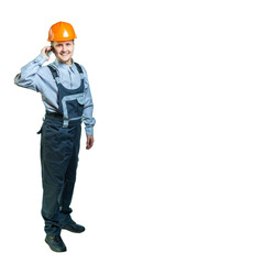 Isolated. Portrait of a worker with overalls and a protective helmet. A cheerful man in overalls receives phone calls.