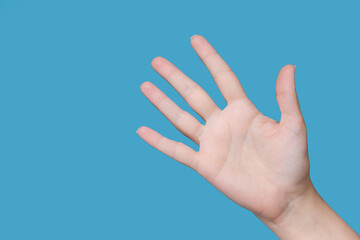 Closeup view stock photography of one beautiful manicured female hand isolated on blue background....