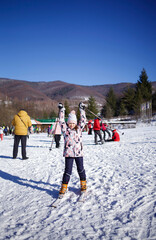girl on skis in winter things. Snow outside. hands up like a winner