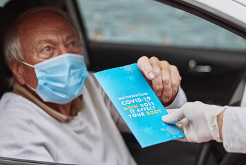 Stay informed about the covid virus. Shot of a senior man taking a pamphlet from a healthcare worker at a drive through vaccination site.