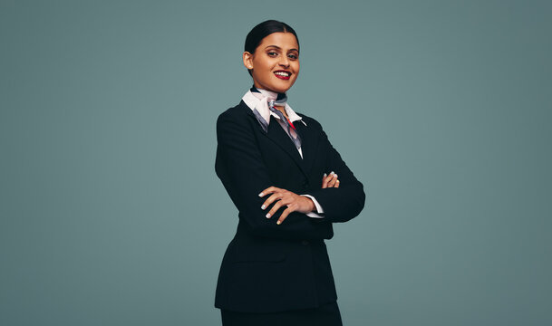 Friendly air hostess smiling at the camera in a studio