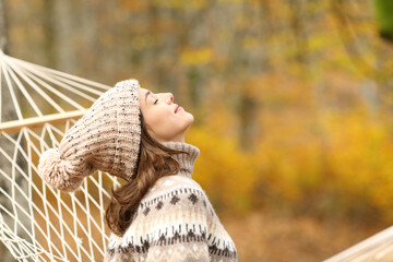 Woman breathing fresh air on hammock in autumn