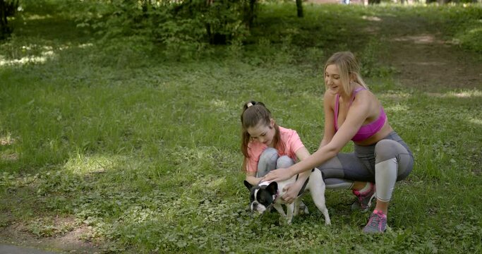 Mother and daughter petting the dog in a park