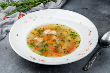 Fish soup on white plate on grey table