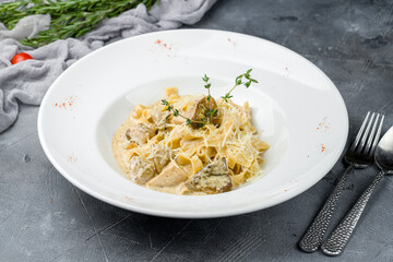 fettuccine with porcini mushrooms on white plate on grey table