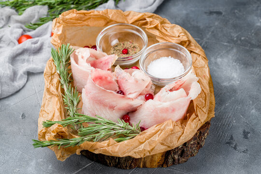 stroganina sliced on the board with salt and pepper on grey table