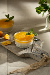 Orange Panna Cotta, a Creamy Italian Pudding with a tropical fruit Gelatin Layer and mint, on wooden Cutting Board. Beautiful summer day. Copy space.