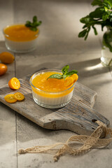 Orange Panna Cotta, a Creamy Italian Pudding with a tropical fruit Gelatin Layer and mint, on wooden Cutting Board. Beautiful summer day. Copy space.