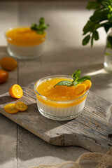 Orange Panna Cotta, a Creamy Italian Pudding with a tropical fruit Gelatin Layer and mint, on wooden Cutting Board. Beautiful summer day. Copy space.