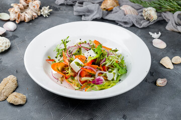 Greek salad with feta, greens and vegetables on grey table