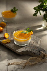 Orange Panna Cotta, a Creamy Italian Pudding with a tropical fruit Gelatin Layer and mint, on wooden Cutting Board. Beautiful summer day. Copy space.