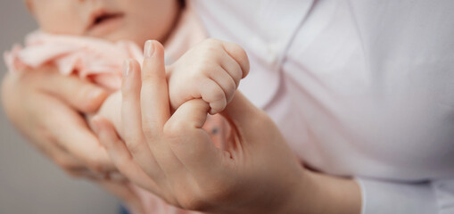 Fototapeta na wymiar Banner Mother with newborn baby hold hands closeup. Concept help and support adoption