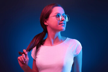 Neon close up portrait of young woman round sunglasses and white dress on dark blue background