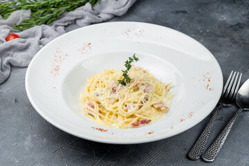 Spaghetti Carbonara with bacon on grey table