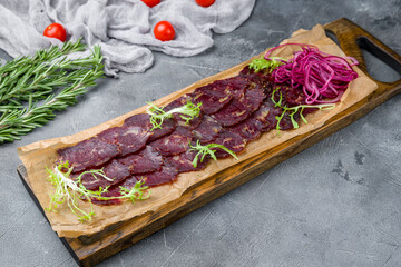 sliced venison sausage on the board on grey table