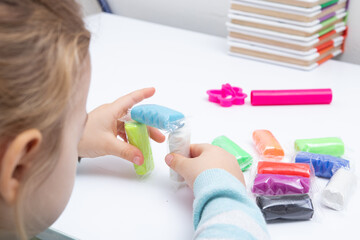 The girl at the table is playing with modeling dough. Childrens games for fine motor skills