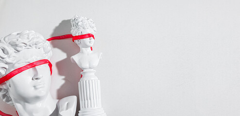 Fake bust of a man and a woman with a red ribbon on their eyes on a white background. The concept...
