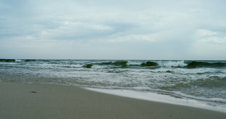 Fototapeta na wymiar Waves crashing sand beach on grey cloudy weather. Aerial view ocean storming.