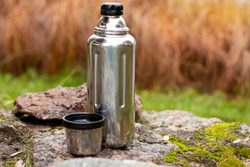 Metal thermos with a mug on the background of nature