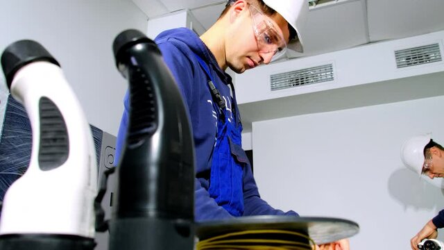 Portable charging station assembling. Engineer worker in protective glasses deals with cables for connecting to pump plugs at workshop