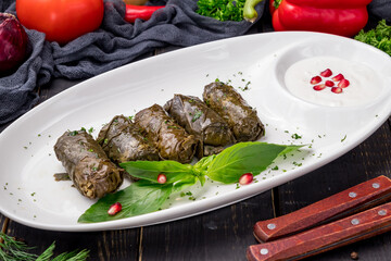 Dolma georgian kitchen with sour cream on white plate on dark table
